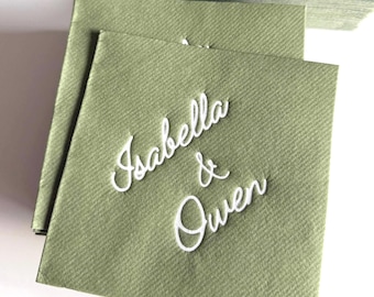 May include: A stack of square sage green paper napkins featuring the white embossed text Isabella & Owen in a cursive script font. The napkins have a textured surface and are arranged in a slightly overlapping pile on a plain white background.