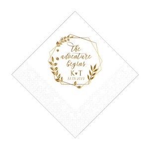 Pu&ograve; includere: Tovagliolo di carta bianco con una cornice geometrica dorata e rami con foglie. Il testo all'interno della cornice dice "The adventure begins K&hearts;T 31.05.2019".