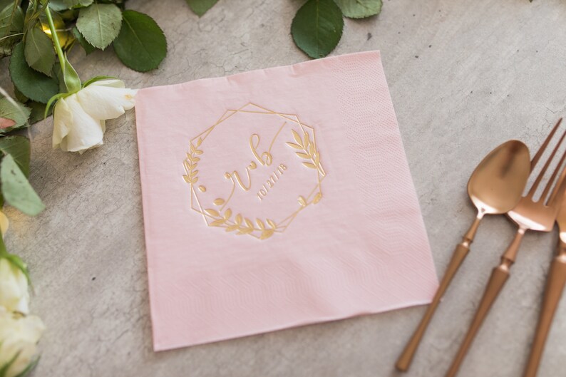 Pu&ograve; includere: Tovagliolo di carta rosa con una cornice geometrica dorata e un motivo floreale. La cornice include il testo "rwb" e la data "10/27/18".