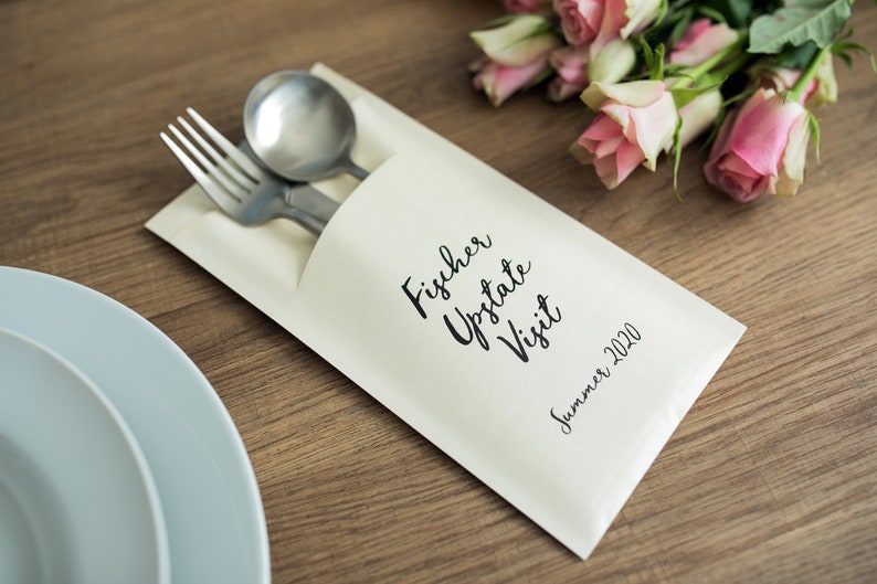 May include: A white paper envelope with a black inscription that reads "Fischer Upstate Visit Summer 2020". A fork and spoon are tucked inside the envelope.