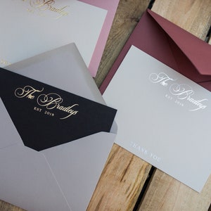 May include: Three stationery note cards with envelopes. The cards are white with a silver inscription that reads "The Bradleys Est. 2019" and "Thank You". The envelopes are burgundy, gray, and black.