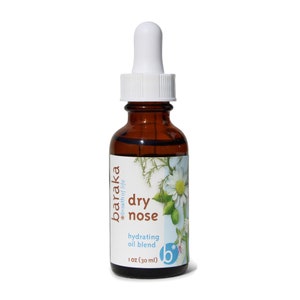 Puede incluir: Una botella de vidrio marrón con un gotero blanco en la parte superior, etiquetada "baraka *breath of life dry nose hydrating oil blend 1 oz (30 ml)". La etiqueta presenta un diseño floral con una margarita blanca.