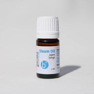 Puede incluir: Una pequeña botella de vidrio marrón con una tapa blanca y una etiqueta. La etiqueta dice "baraka #breath of life" y "Steam Oil open lungs". La botella contiene 5 ml de aceite.