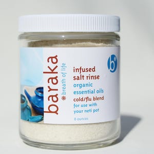 May include: A clear glass jar with a white lid filled with white powder. The label reads "baraka *breath of life infused salt rinse organic essential oils cold/flu blend for use with your neti pot 8 ounces".