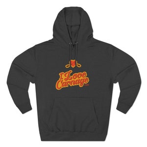 Può includere: Una felpa con cappuccio grigio scuro con un cuore rosso e il testo "I Love Carnage" in lettere arancioni e gialle.