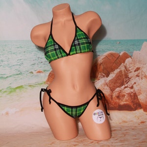 Puede incluir: Bikini de cuadros verdes y negros con un top halter y una parte inferior de lazo lateral. El bikini está hecho de una tela de malla transparente.