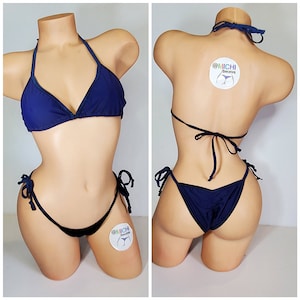 May include: Navy blue bikini with a halter top and a tie-side bottom. The bikini is made of a soft, stretchy fabric. The bikini top has a triangle shape and the bottom has a low-rise cut. The bikini is decorated with a small, round sticker that says "@MICHI bikinis".