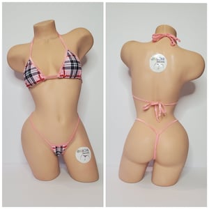 Puede incluir: Bikini de cuadros rosa y negro con tirantes finos y parte inferior de cuerda. El bikini está en un maniquí. El bikini tiene un pequeño logotipo en la parte inferior que dice "@Michi Bikinis".