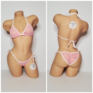 Puede incluir: Conjunto de bikini de malla rosa con ribetes blancos y lazos ajustables. La parte superior e inferior del bikini tienen una pequeña etiqueta con el texto "@NICHI Designs".