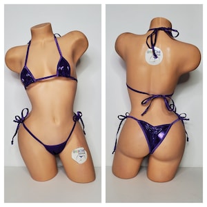 May include: Purple metallic bikini with a halter top and a low-rise bottom. The bikini has adjustable straps and ties at the sides. The bikini is on a mannequin.