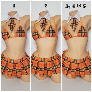 Puede incluir: Una falda a cuadros y un top de bikini a juego con cuello blanco y corbata. El conjunto es naranja, negro y blanco.