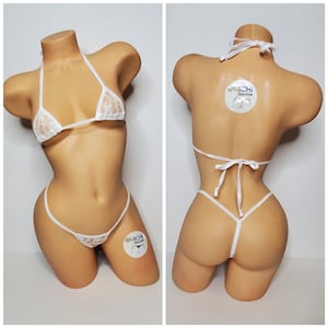 Puede incluir: Bikini blanco de encaje con top triangular y parte inferior de tanga. El bikini está en un maniquí. El nombre de la marca "@Michi Bikinis" está en la parte inferior derecha de la imagen.