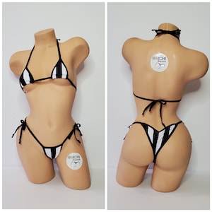 May include: Black and white striped bikini with thin straps and a tie at the back. The bikini is on a mannequin. The bikini has the text "@michi bikinis" on the bottom.