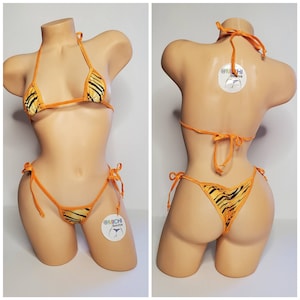May include: Orange and black striped bikini with a halter top and a tie-side bottom. The bikini is on a mannequin. The tag on the bikini reads "@MICHI Bikinis".