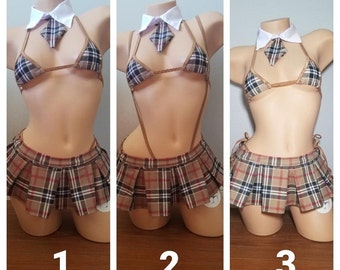Op de afbeelding: Drie mannequins dragen een bruin en zwart geruite rok en een bruin haltertop met een witte kraag en een bruine stropdas. De mannequins zijn genummerd 1, 2 en 3.