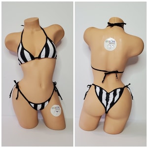 May include: Black and white striped bikini with a halter top and a cheeky bottom. The bikini has a tie at the sides and a string tie at the back. The bikini is on a white mannequin.