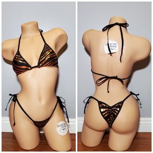 May include: Black and gold zebra print bikini with adjustable straps and ties. The bikini top and bottom have a triangle shape. The bikini is on a mannequin.