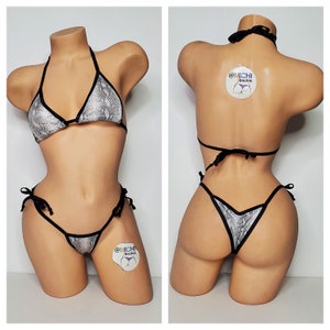 Puede incluir: Un bikini de estampado de piel de serpiente negro y plateado con tirantes y lazos ajustables. La parte superior del bikini es de estilo triangular y la parte inferior es de estilo atrevido. El bikini está hecho por @MICHI bikinis.