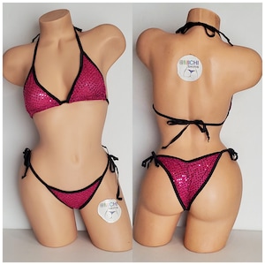 Pode incluir: Um biquíni rosa com lantejoulas e acabamento preto. A parte de cima do biquíni é de estilo triangular e a parte de baixo é de estilo atrevido com laços nas laterais. O biquíni é mostrado em um manequim.
