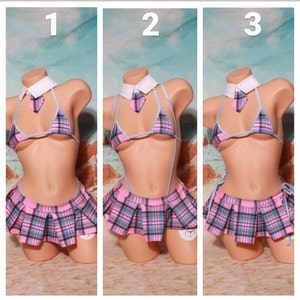 May include: A pink and blue plaid skirt with a matching bikini top and a white collar with a blue tie. The outfit is styled as a school girl costume.