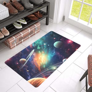 May include: A colorful space-themed doormat with a galaxy background and planets, including Saturn with its rings, in shades of blue, green, orange, and purple.