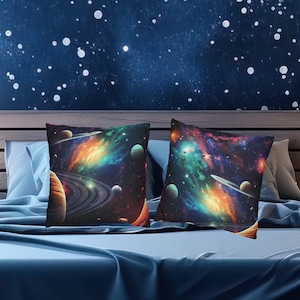 May include: Two decorative throw pillows with a space-themed design. The pillows feature a dark background with colorful nebulae, stars, and planets.