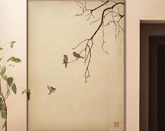May include: A minimalist interior design with a large framed print of a branch with birds on a beige wall. The print is in a light brown frame and is hanging above a white bench with a brown stone sculpture on it.