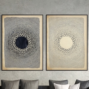 Può includere: Due stampe d'arte astratta incorniciate con motivi circolari in bianco e nero. Le stampe sono appese a una parete grigia sopra un divano grigio con cuscini.