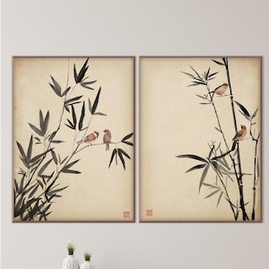 Può includere: Due opere d'arte da parete incorniciate. Ognuna presenta un ramo di bambù con piccoli uccelli appollaiati. L'opera d'arte è in stile asiatico tradizionale, con inchiostro nero su sfondo color crema. Le cornici sono di colore marrone scuro.