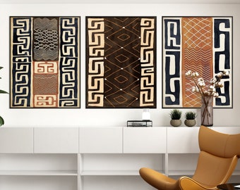 May include: Three framed abstract art prints with geometric patterns in black, brown, and white. The prints are hung on a white wall above a white shelf unit with a brown leather chair.