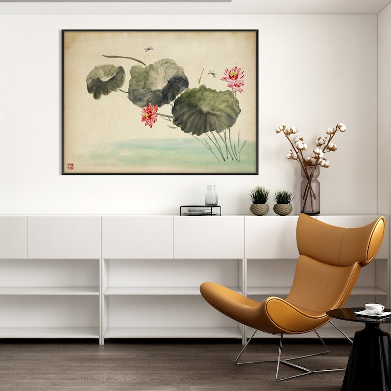 May include: A framed watercolor painting of lotus flowers and leaves in a serene, Asian-inspired style. The artwork features pink blossoms, large green leaves, and dragonflies, set against a soft, neutral background. The painting is displayed above a white cabinet.