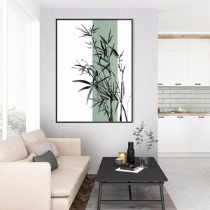 May include: A black and white illustration of bamboo plants with a green background. The illustration is framed and hanging on a white wall in a living room setting.