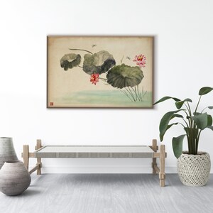 May include: A framed watercolor painting depicts lotus flowers and lily pads in a serene pond. The artwork features soft greens, pinks, and muted earth tones, with delicate brushstrokes and a touch of Asian-inspired artistry. The painting is displayed above a wooden bench.