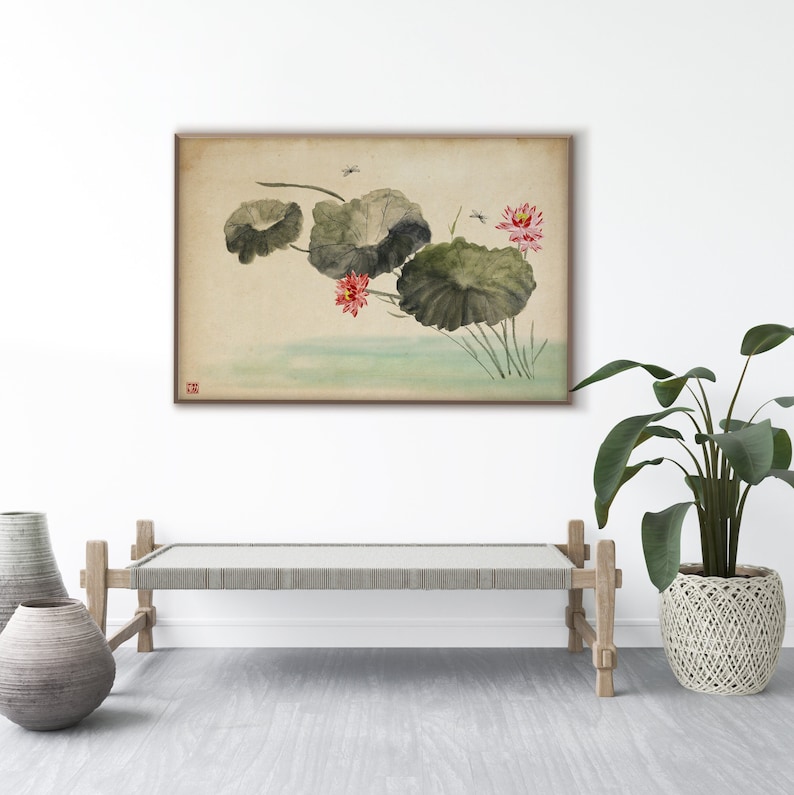 May include: A framed watercolor painting depicts lotus flowers and lily pads in a serene pond. The artwork features soft greens, pinks, and muted earth tones, with delicate brushstrokes and a touch of Asian-inspired artistry. The painting is displayed above a wooden bench.