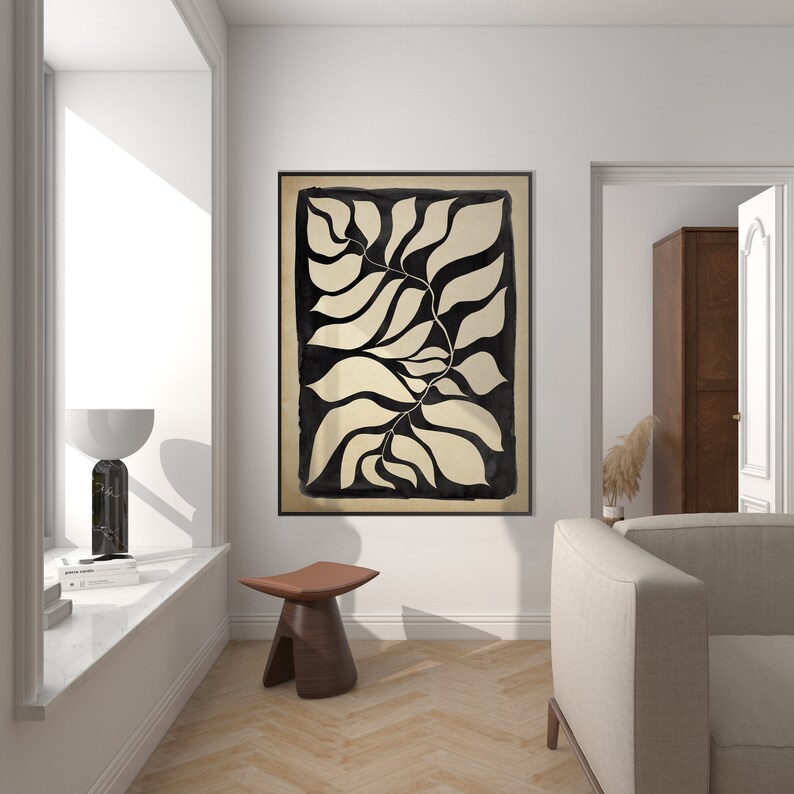 May include: A black and white abstract art print of stylized leaves in a minimalist style. The print is framed and hanging on a white wall in a modern living room.