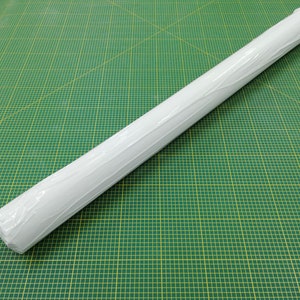 Puede incluir: Un rollo de papel blanco envuelto en pl&aacute;stico transparente, sobre una estera de corte verde con l&iacute;neas de cuadr&iacute;cula amarillas.