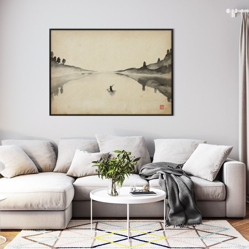 Puede incluir: Una pintura de tinta negra y blanca de una figura solitaria en un bote en un lago tranquilo. La pintura est&aacute; enmarcada y colgada en una pared sobre un sof&aacute; blanco.