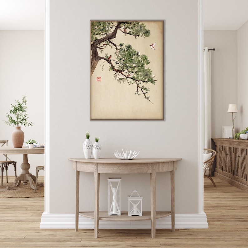 Pode incluir: Uma obra de arte emoldurada com uma pintura em aquarela de um galho de pinheiro com agulhas verdes e pequenos p&aacute;ssaros. A obra de arte tem um fundo bege e &eacute; exibida em uma parede branca acima de uma mesa de console de madeira.