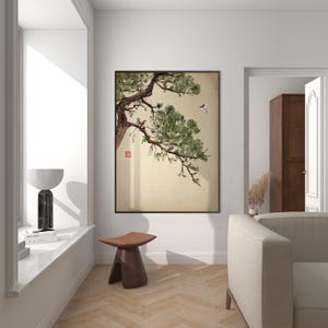 Pode incluir: Uma impress&atilde;o de arte emoldurada com uma pintura em aquarela de um galho de pinheiro com p&aacute;ssaros. A obra de arte tem um fundo bege e uma moldura preta. A impress&atilde;o &eacute; exibida em uma sala bem iluminada com uma est&eacute;tica moderna.