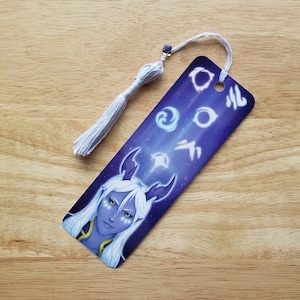 May include: A purple and white bookmark featuring a character with white hair and blue skin. The bookmark has a white tassel and symbols of the four elements: water, earth, fire, and air.