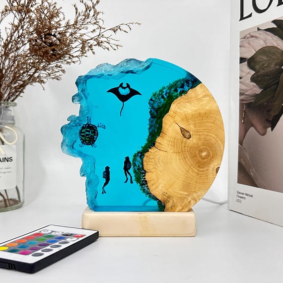 Sea turtles and manta rays rendered in glowing ocean-blue epoxy resin set into a wood base — coastal art that actually lights your room.