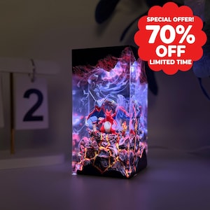 Può includere: Una lampada rettangolare in resina con una miniatura di drago rosso su una base vulcanica testurizzata con crepe di lava arancione brillante. L'interno è riempito con effetti di fumo viola e blu, illuminato da luci LED interne.