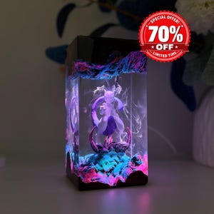May include: A rectangular resin lamp featuring a purple and white Mewtwo figure encased in clear material. The base and top are black, with internal blue and pink LED lighting illuminating swirling smoke-like patterns. A red circular badge reads 70% OFF LIMITED TIME.