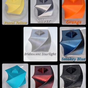 May include: A collage of 3D-printed geometric sculptures in various colors. Colors include pastel yellow, silver, orange, iridescent starlight, smokey blue, tiffany blue, red nebula silk, and black glitter. Each sculpture has a square pyramid on top.