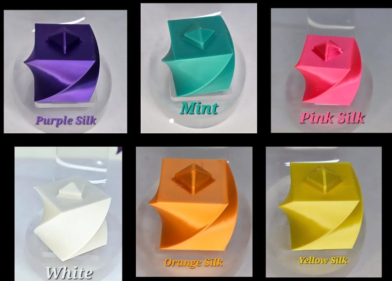 May include: Six small cube-shaped objects with a twisted design and a pyramid top, displayed in purple silk, mint, pink silk, white, orange silk, and yellow silk colours. Each cube features a smooth finish and is labelled with its respective colour name.