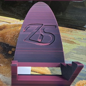 May include: A red nebula diamond art container holder. The holder is made of a dark red material and features the letters "ZS" in the center. The text "Fits Diamond Art Club and Elizabeth Ward Containers" is at the top.