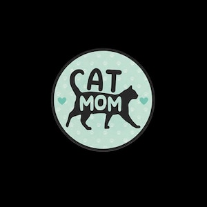 May include: A circular sticker featuring a light mint green background with a repeating pattern of small white paw prints. A black silhouette of a walking cat is centred, with the text CAT MOM in white letters inside the cat's body.
