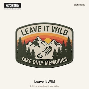 Puede incluir: Un parche bordado que mide 6,35 cm en su punto más largo, con un paisaje de montaña con pinos, un sol amarillo y una huella de bota. El texto dice LEAVE IT WILD y TAKE ONLY MEMORIES en letras de color verde oscuro.