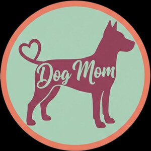 Puede incluir: Una pegatina circular con la silueta granate de un perro de pie de perfil. La cola del perro está curvada en forma de corazón. El texto "Dog Mom" está escrito en una fuente cursiva blanca sobre el cuerpo del perro. El fondo es verde claro.