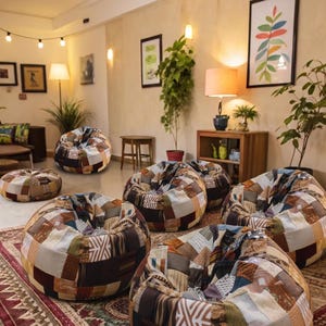 May include: A collection of round, low-profile floor cushions featuring a patchwork design composed of various fabric squares in shades of brown, tan, cream, and grey with diverse geometric and textured patterns, arranged across a patterned area rug.